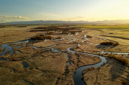 Aerial photograph of wetland with paddocks and mountains in the background