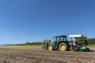 Tractor in a ploughed paddock with a planting unit on the back planting leeks